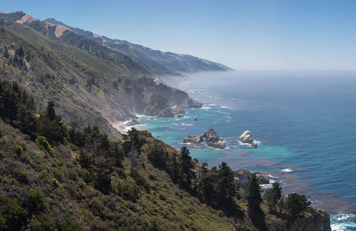 Scenic view of a legendary American road route along a rugged coastline with cliffs and ocean waves.