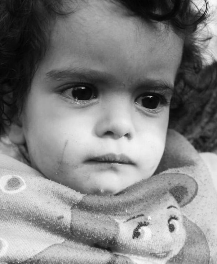 Black and white photo of a child with a thoughtful expression, illustrating childhood's innocence and resilience.