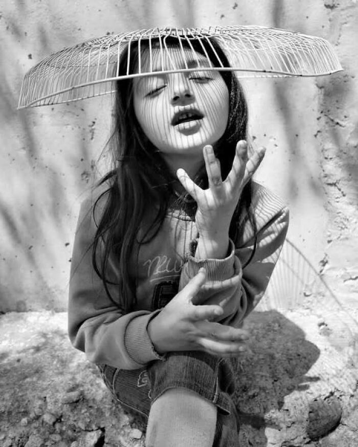 Childhood captured in black and white; a girl poses with shadows on her face, embodying innocence and resilience.