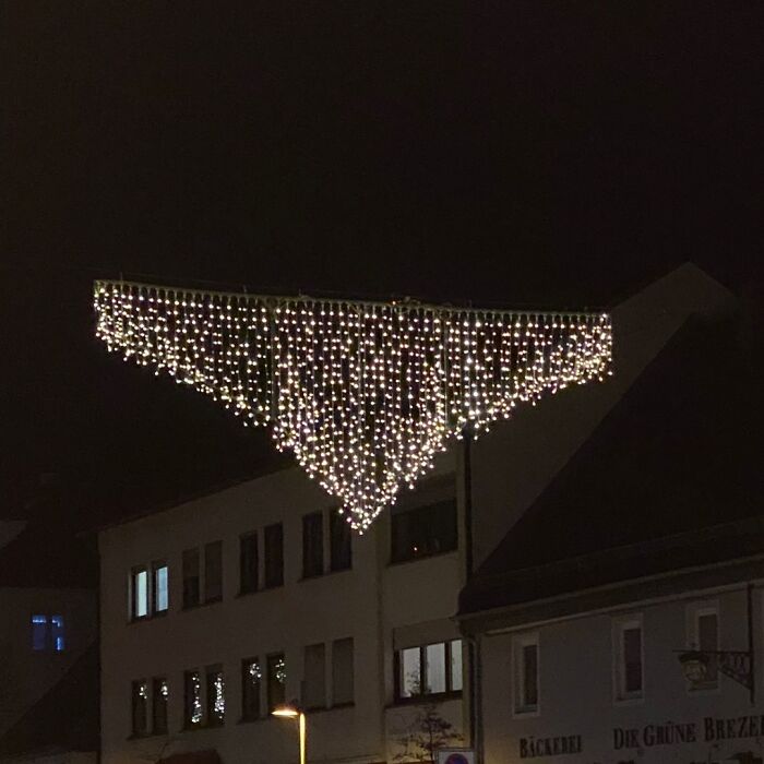 Triangle-shaped string lights hang awkwardly between buildings, illustrating a humorous design fail.