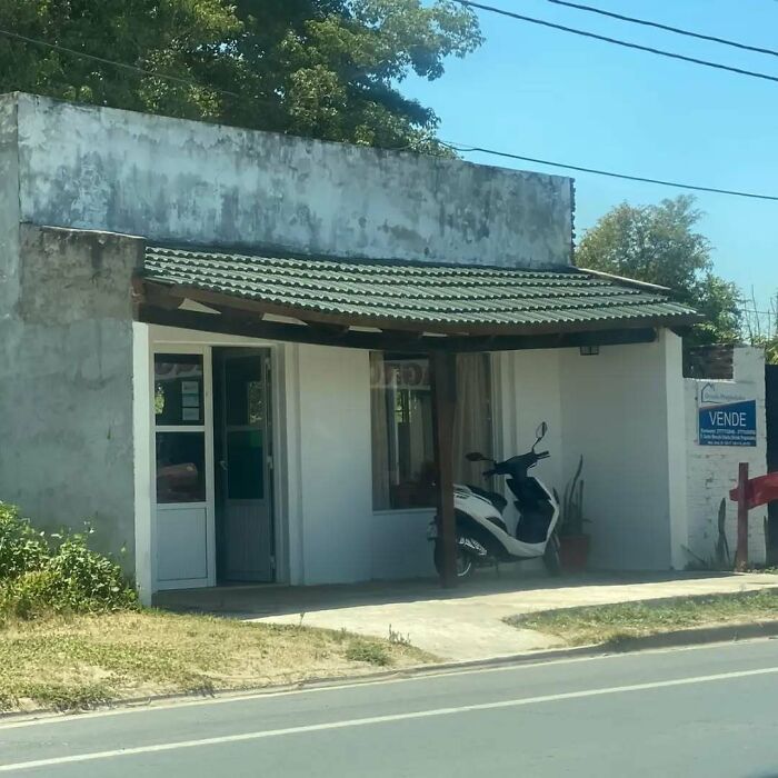 Scooter parked inside a small structure with a tilted roof, showcasing architecture fails.