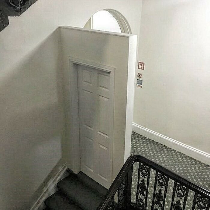 Staircase leading to a wall with a door to nowhere, showcasing a design fail.