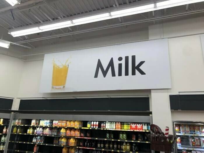 Supermarket sign reading "Milk" with an orange juice image, illustrating a design fail.