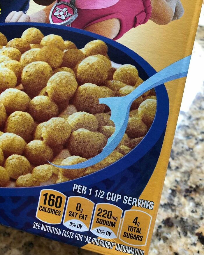 Cereal box design with spoon printed awkwardly over nutritional information, featuring a cartoon character in the background.