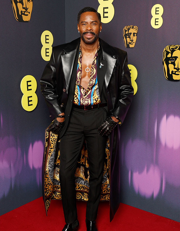 Man in a daring outfit with a patterned shirt and leather coat at the Bafta red carpet.