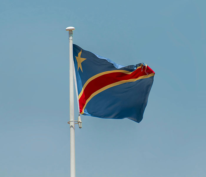 Flag of the Democratic Republic of the Congo flying under a clear sky, linked to unknown illness crisis. Flag of the Democratic Republic of the Congo flying under a clear sky, linked to unknown illness crisis.