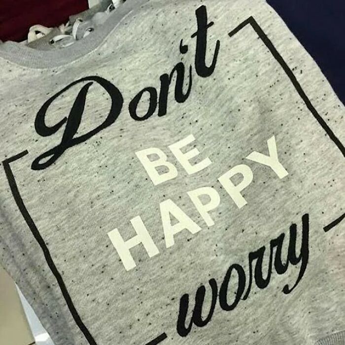 Sweatshirt design fail with confusing "Don't Be Happy Worry" slogan in black and white text.