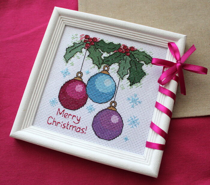 Framed digital cross stitch pattern featuring Christmas ornaments and holly with "Merry Christmas" text.