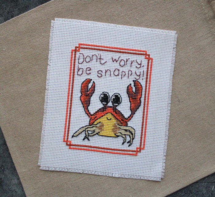 Digital cross stitch pattern featuring a cheerful crab with the text "Don't worry be snappy!" in red and beige tones.