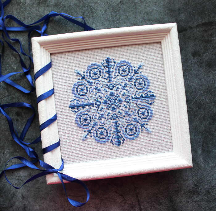 Framed digital cross stitch pattern with blue geometric design and ribbon accent.
