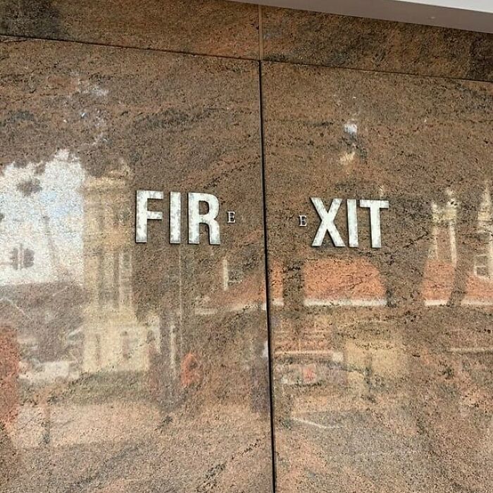 Fire exit sign design fail on a reflective wall, showing confusing letter placement.
