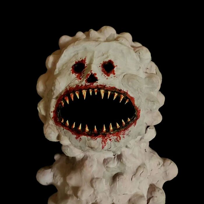 Creepy handmade craft with a ghostly face and sharp teeth on a dark background.