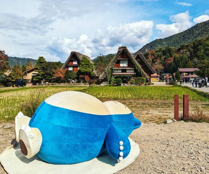 Sleeping Snorlax statue in a rural Japanese village with traditional houses, capturing Interesting-Japan-Pics atmosphere.