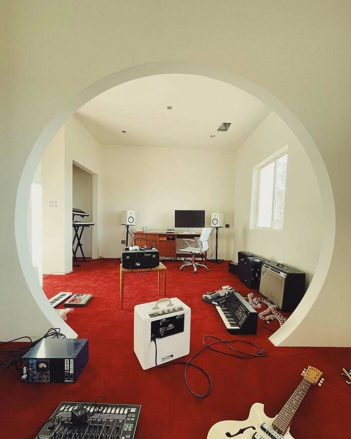 Modern home studio with quirky decor, featuring music equipment, a computer desk, and a red carpet.