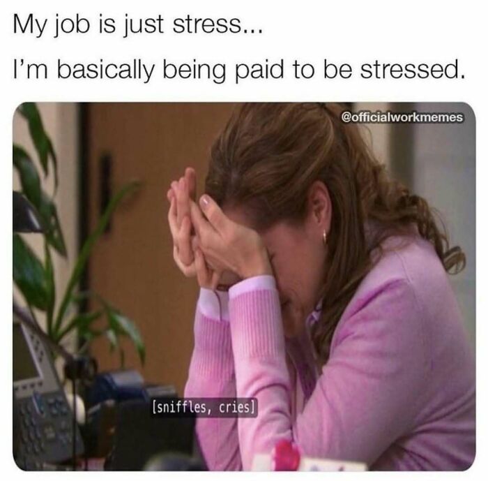 Overworked employee stressed at desk, head in hands, with "being paid to be stressed" meme text above.