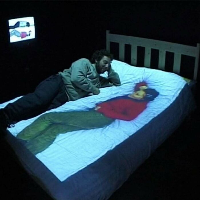 Man lying on a bed with a strange image projected onto it, highlighting the internet's bizarre nature.