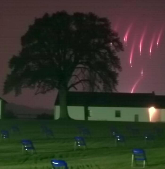 Liminal space with empty chairs, a tree, and glowing lights in the sky creating an eerie atmosphere.