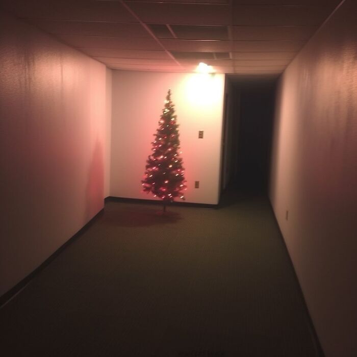 Dimly lit hallway with a single Christmas tree, evokes eerie liminal space atmosphere.
