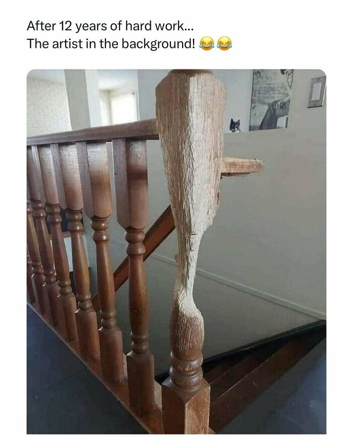 Wooden stair rail with a worn middle post, humorous cat photo in background, bringing a little joy to your day.