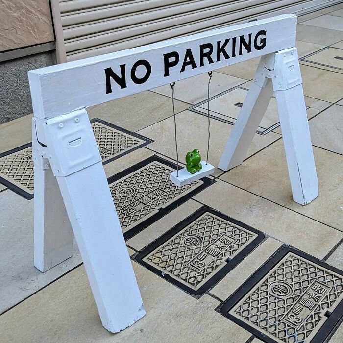 No parking sign in Japan with a cute frog on a swing underneath, creating an interesting scene.