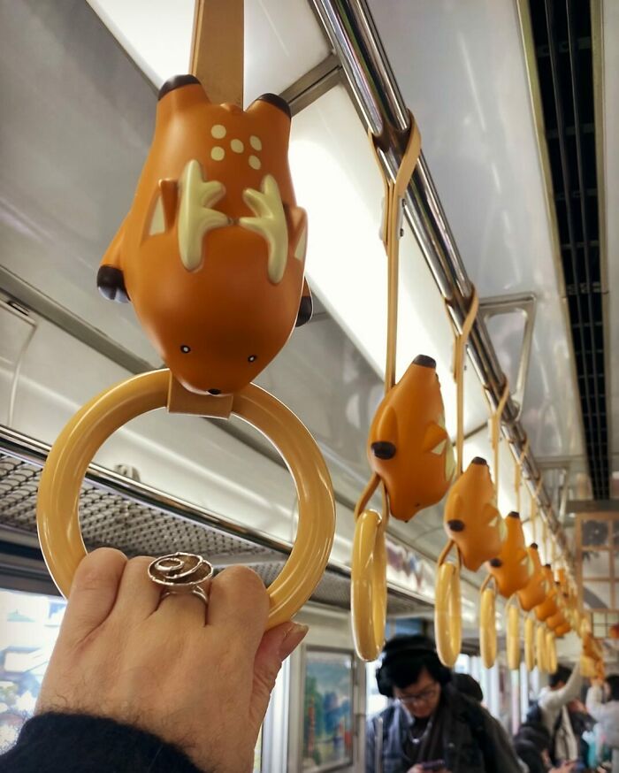 A train passenger holds a cute animal-shaped handle in Japan, showcasing unique design.