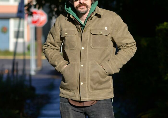 Man wearing a durable, beautifully designed khaki jacket, standing outside on a sunny day.