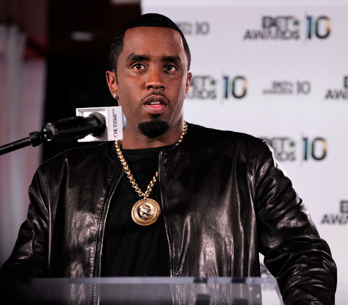 Man in black leather jacket speaking at a podium during an event, related to lawyer's trial quit.