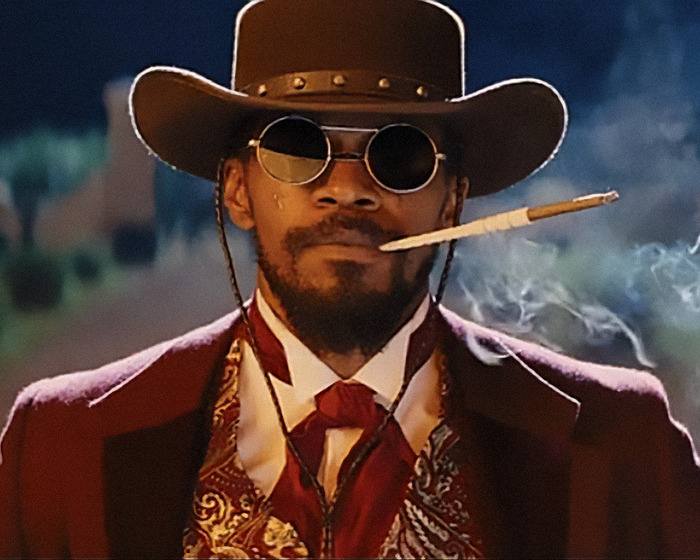 Man in period costume with hat and sunglasses, smoking a cigarette. Hollywood's historical inaccuracies depicted.