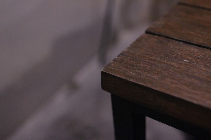 Wooden table edge on a shadowy background, relating to superstitions about corners and energy flow.
