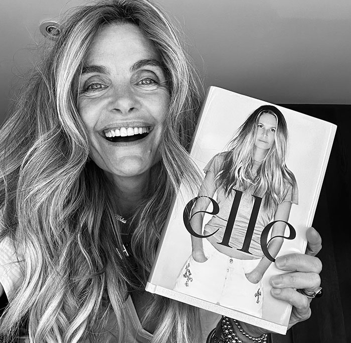 Person smiling holding a magazine with the title "Elle" visible, related to discussion on Photoshop. Person smiling holding a magazine with the title "Elle" visible, related to discussion on Photoshop.