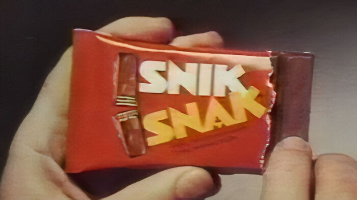 Hand holding a Snik Snak chocolate bar from the 90s and 2000s, partially unwrapped.
