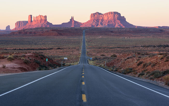 A scenic view of a famous American road stretching towards rocky formations under a clear sky.