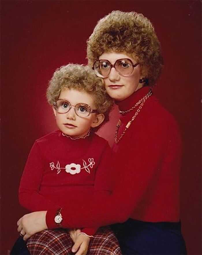1980s epic hair disasters: Woman and child with curly hair and glasses, both wearing red.