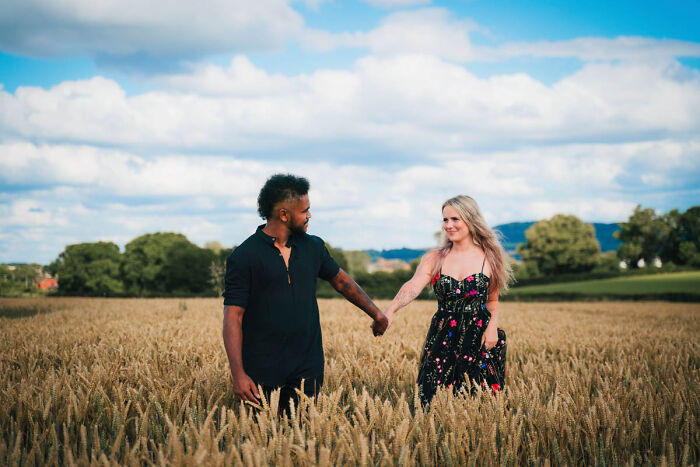 A couple holding hands in a wheat field under a blue sky, part of best wedding photographs collection.