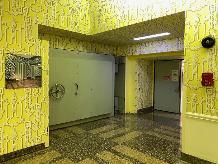 Yellow-walled room with a large metal door, reminiscent of weird government projects.