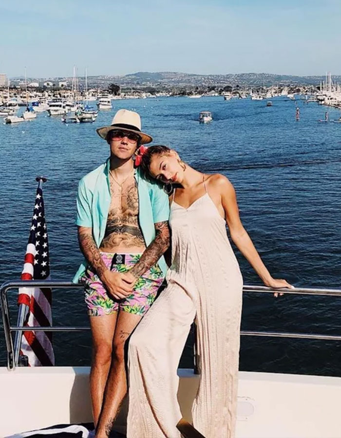 Two people in budget-friendly summer outfits on a boat with ocean backdrop.