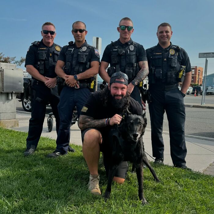 A group of police officers with K9 Hurricane, a decorated police dog, sitting on the grass. A group of police officers with K9 Hurricane, a decorated police dog, sitting on the grass.