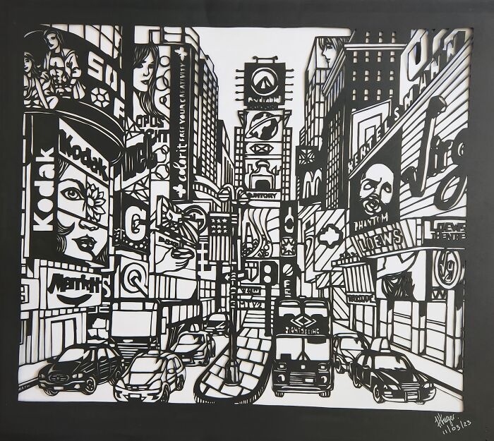 Hand-cut paper artwork depicting a detailed cityscape with buildings and cars.