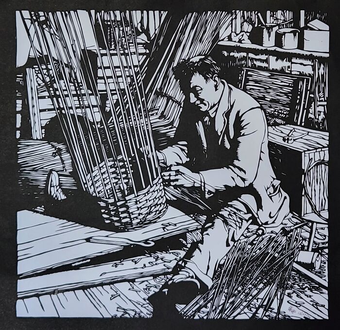 Hand-cut paper artwork depicting a man weaving a basket.