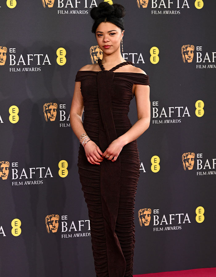 Person in a glamorous outfit on the BAFTA red carpet, showcasing daring fashion choices.