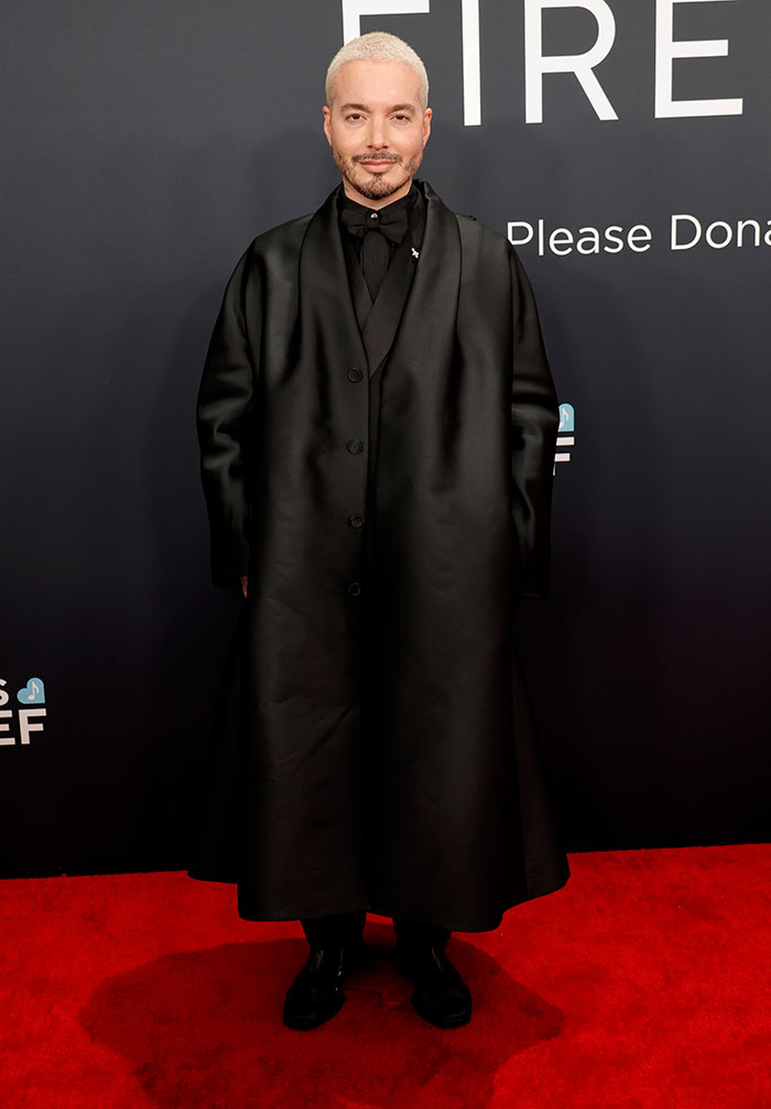 Man in a long black coat on red carpet at 67th Grammy Awards.