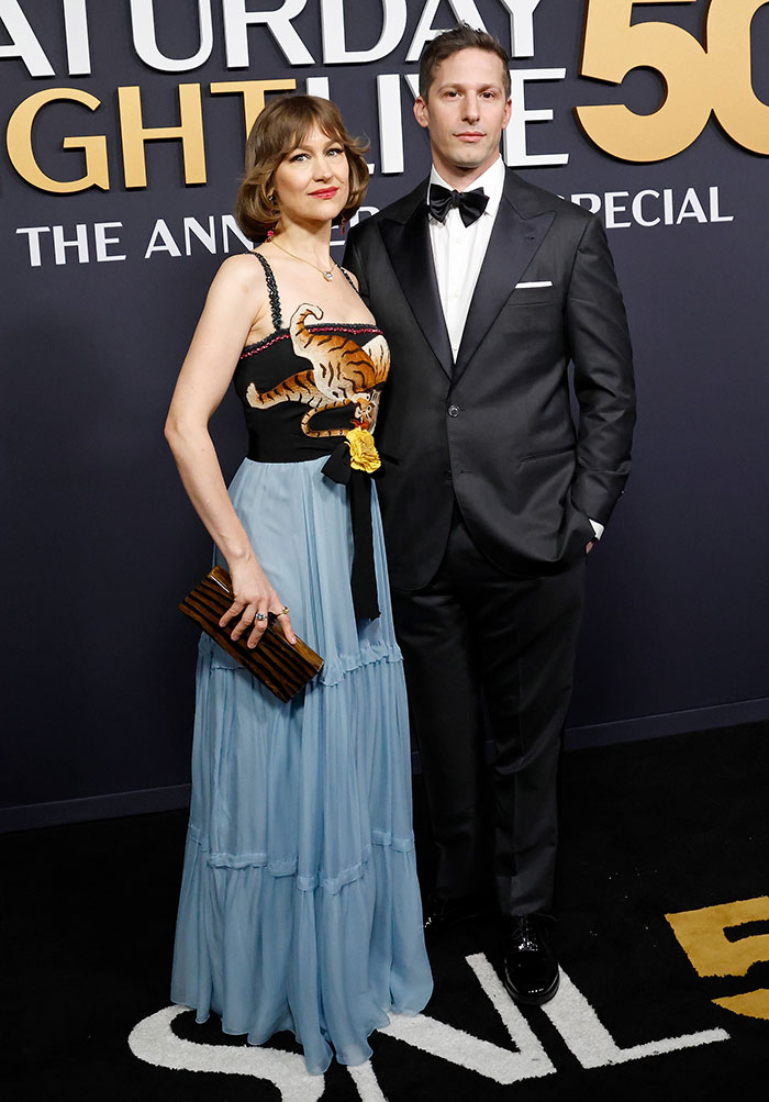 A couple poses in unique outfits at the SNL 50th anniversary event red carpet.