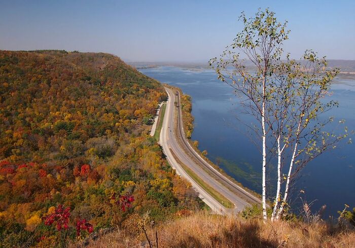 Scenic view of Legendary American road route beside autumn-colored hills and river.
