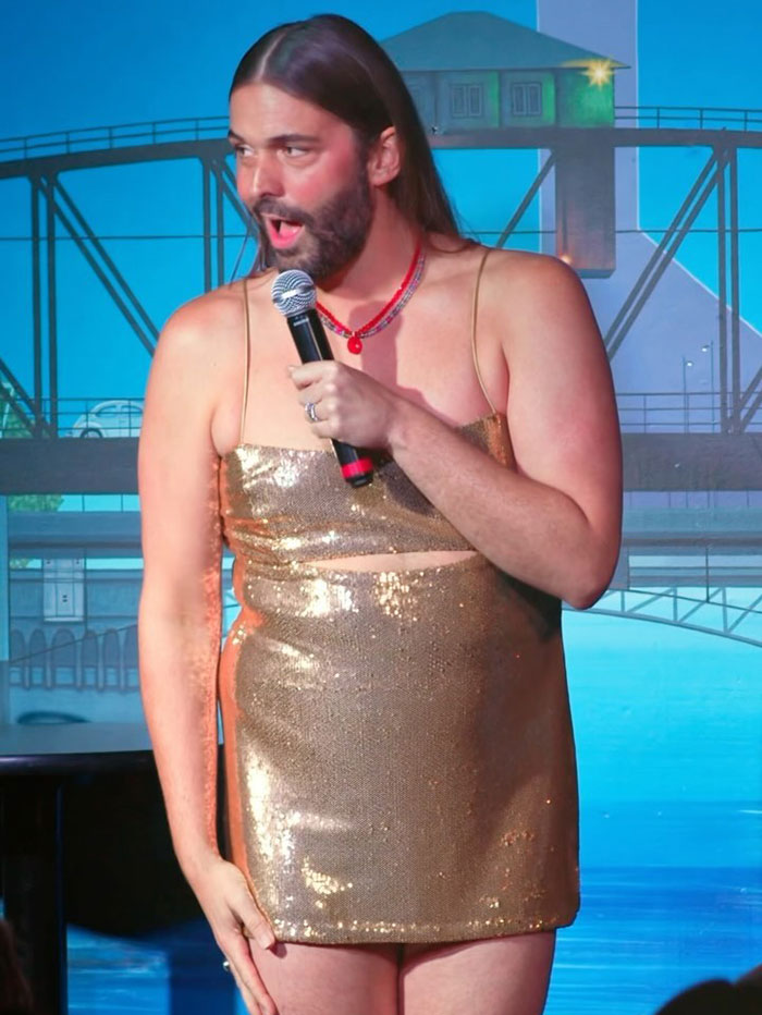 Queer Eye's Jonathan Van Ness on stage in a gold dress during a performance.