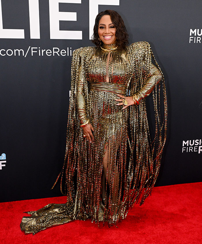 Woman in a shimmering gold dress with fringe details on the red carpet at the 67th Grammy Awards.