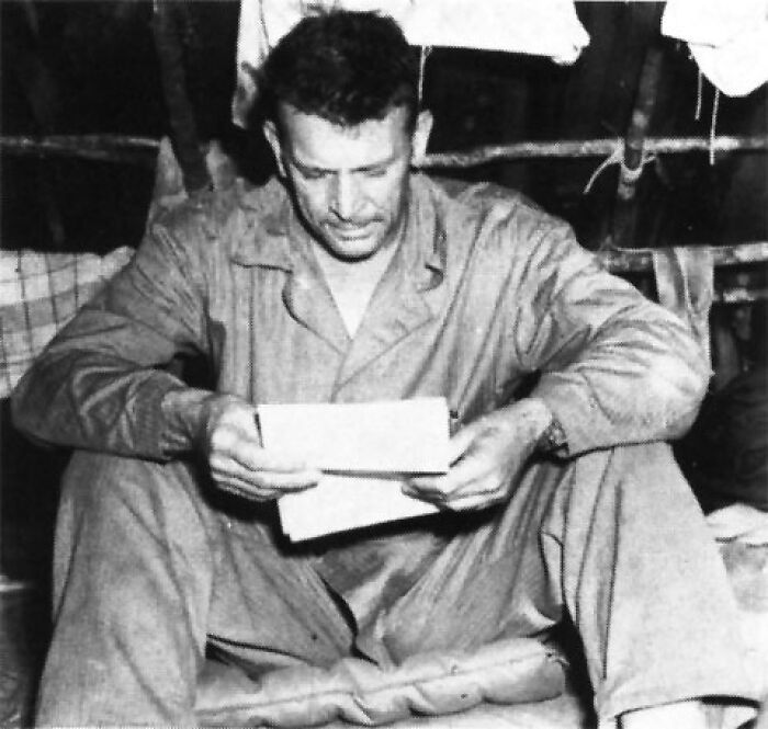 A person in casual attire, sitting and reading a document related to weird government projects.
