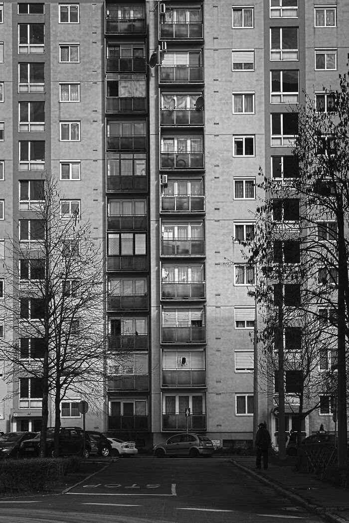 Hungary’s panel building in black and white, featuring urban architecture and parked cars in the foreground.