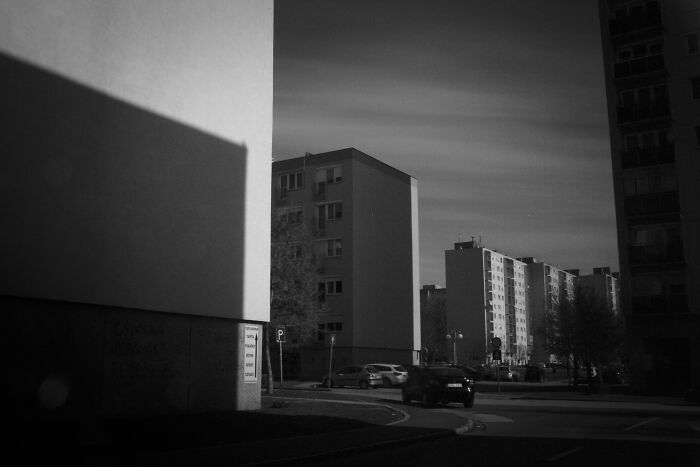 Black and white photo of Hungary's panel buildings with cars parked on the street.