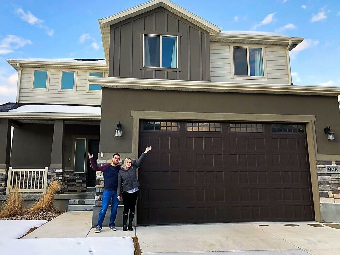 Couple standing outside their house celebrating the journey of their cat becoming a house cat after six years.