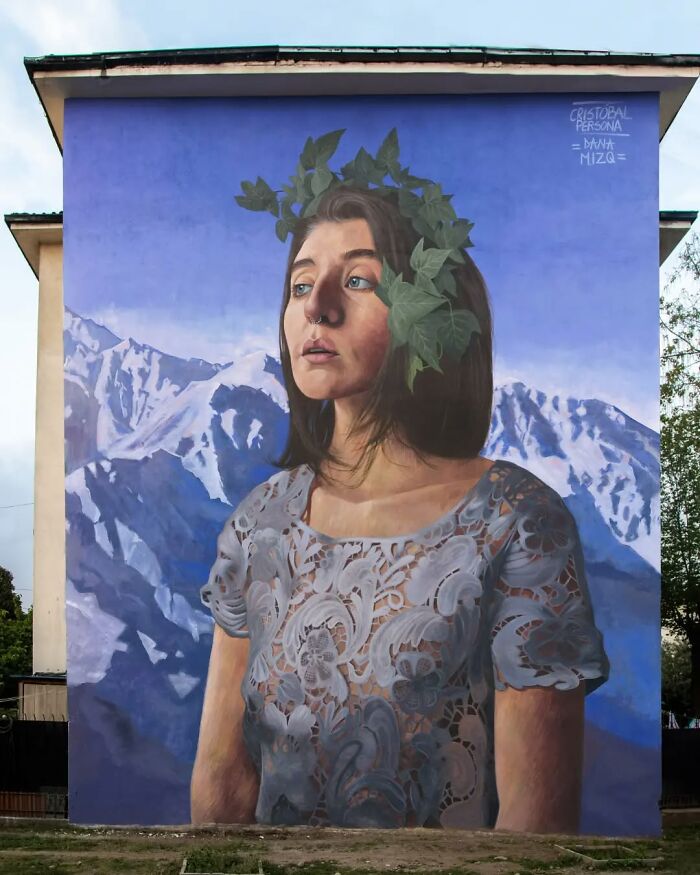 Chilean artist's mural of a woman with a leafy crown against a mountain backdrop, showcasing breathtaking artistry.